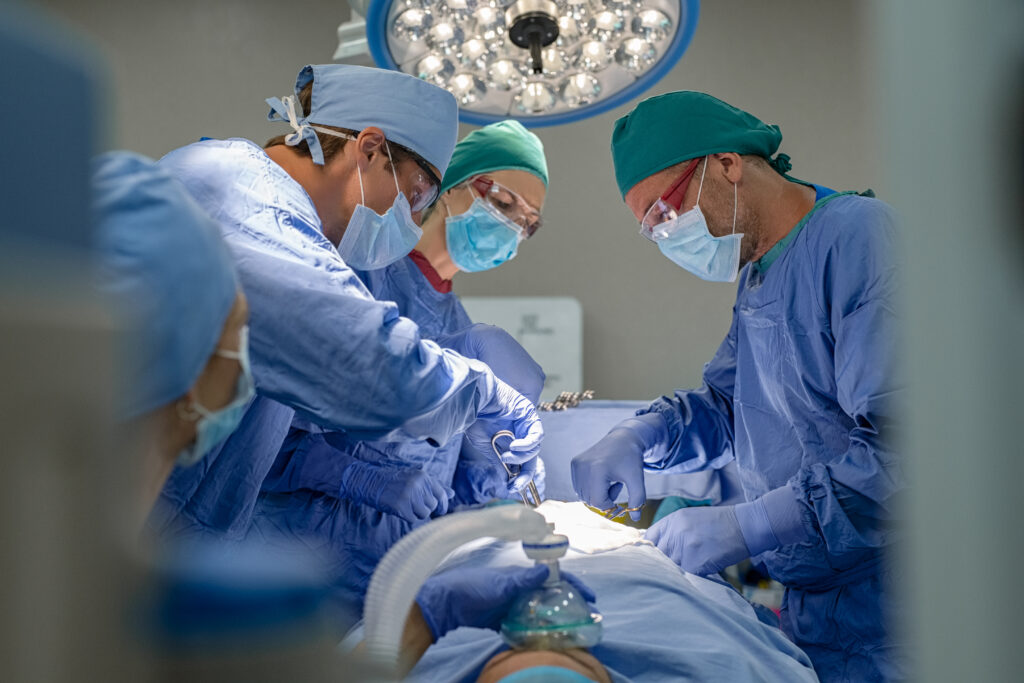 Medical team performing surgical operation in modern operating room. Surgery staff operating in a surgical room at hospital. Concentrated surgeons working on patient in an operation theater.